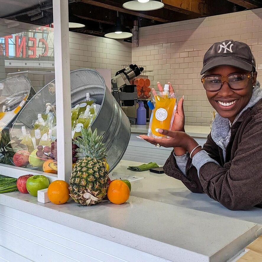 Rhonda Faison, owner of rōJō Juice holds up fresh squeezed organic orange juice at her shop in Pike Place Market in Seattle.